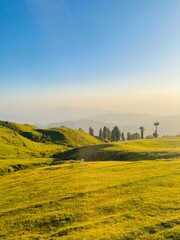 Golden Glow on Rolling Green Hills and Layered Mountains