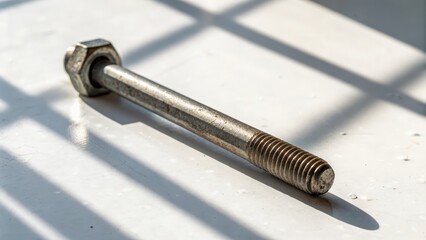 Close up of a bolt with shadows on a surface highlighting metal texture and detail