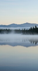 Fototapeta premium Misty lake scene with silhouetted mountains and trees
