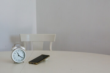 An analogic clock next to a mobile phone on a white background symbolizes the passage of time spent in front of screens. Concept: social issues