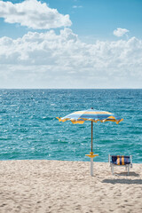 Summer beach scene with umbrella and chair by the sea, vacation and relaxation concept.
