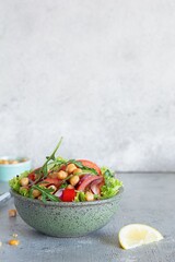 Healthy Vegetarian Chickpea Salad in a bowl with vegetables, herbs and dressing on a blue background. Healthy food concept, A dish of oriental cuisine.