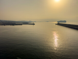 Szene am Hafen der Jeju-Insel: Schiffe, Kr&auml;ne und K&uuml;stengeb&auml;ude pr&auml;gen das maritime Bild, eingerahmt von klarer Sicht und ruhigem Wasser. S&uuml;dkorea.