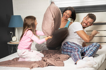 Happy young family having a pillow fight