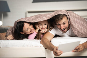 Funny way for a family to use a tablet in bed.