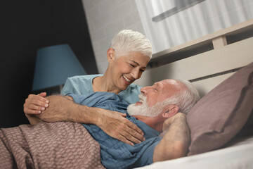 Happy senior couple embracing tenderly on bed at home