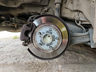 Close-up of disc brake assembly with the wheel removed, showing the caliper, polished rotor, and wheel hub with mounting studs.