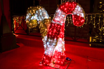 Colorful illuminated candy cane decoration with festive lights creating a cheerful holiday atmosphere in a cozy setting © Inga Bulgakova