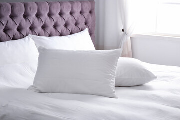 Modern bed with soft pillows in room