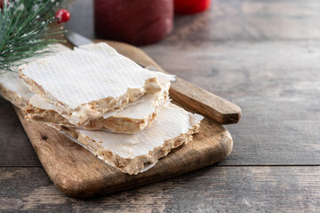 Traditional Christmas sweet, pieces of delicious almond nougat on wooden table. Copy space