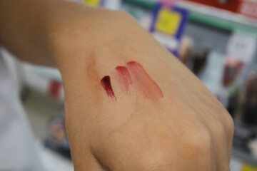 Hand holding three different colored lipsticks