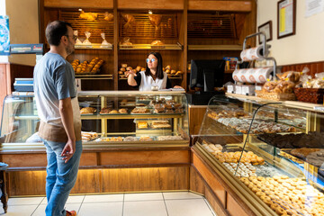 Customer interacting with saleswoman at local bakery shop