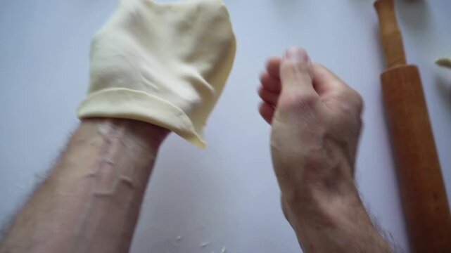 The man rolls ball of dough into flatbread, then take on and tousses it in air