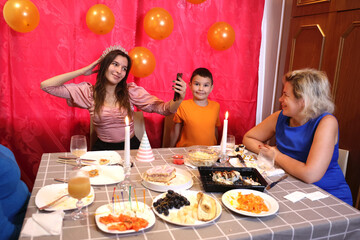A girl with her family is sitting at the table and celebrating her birthday. Soft lighting.