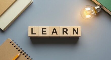 Wooden blocks spell learn next to glowing light bulb and books
