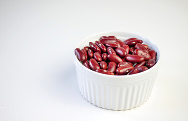 Red bean seeds in a white bowl on a white background