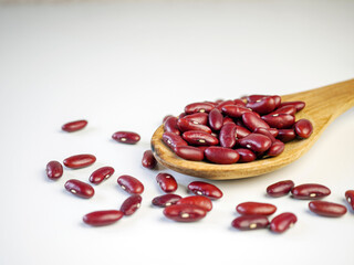 Red bean seeds on a wooden spoon on a white background