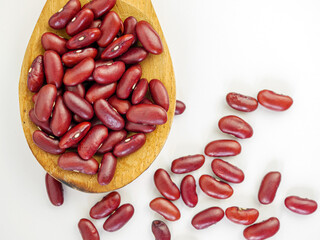 Red bean seeds on a wooden spoon on a white background