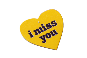 A yellow heart-shaped tag with the phrase "i miss you" written on it, with a dark background