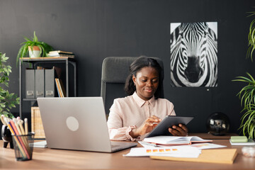 Black businesswoman working on tablet in modern office