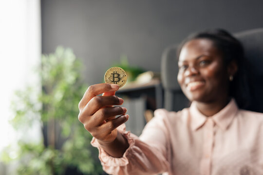 African american woman holding up a bitcoin coin