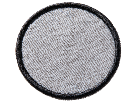 Circular, patch-like item with a rough texture. A black border surrounds the grey center