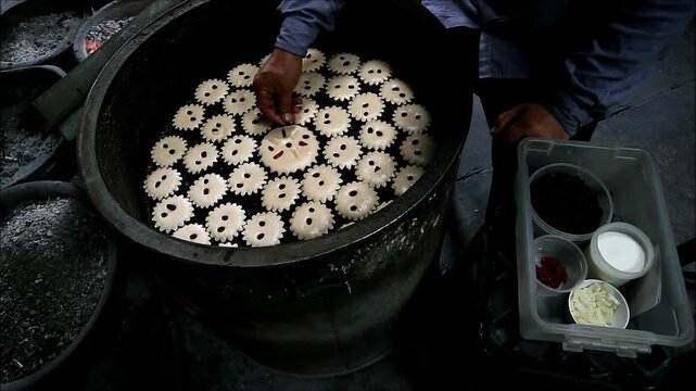Baker Adding Dried Fruit Chunks and Springling Sugar on Portuguese-Siamese Kudeejeen Cupcakes Mid-baked Batter in a Brazier