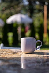 A Tranquil Morning Scene Featuring a Simple Yet Elegant Coffee Mug Resting on a Beautifully Polished Table, Surrounded by Lush Greenery and Soft Background Lights