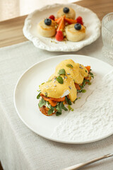 Bruschetta with poached eggs, smoked salmon, arugula and hollandaise sauce on a white plate