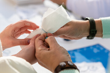 Two people's hands are bandaged with a piece of cloth. The action of working with the material.