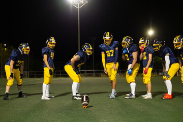 American football players preparing for night kickoff