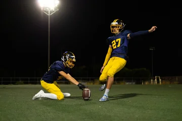 Fototapeten Fußball American football players attempting field goal at night  © luisrojasstock