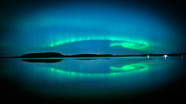 Nortern lights dancing over calm lake in Farnebofjarden national park in north of Sweden