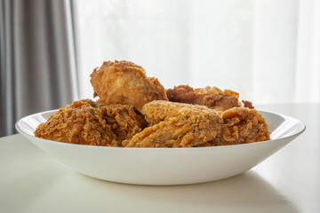 Crispy fried chicken in white plate on wood table