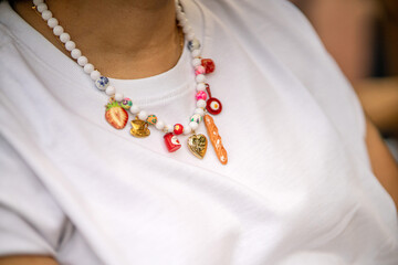 Close-up of a woman wearing a culinary-themed necklace at a food festival. The necklace features cooking utensils and food motifs, adding a creative touch to her festival attire.