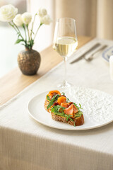 Salmon bruschetta with arugula and sesame bread served on a plate with wine on elegant table setting