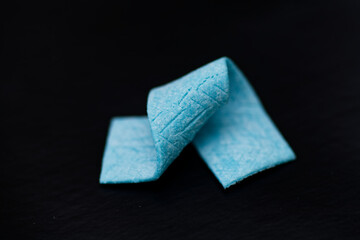 Blue Chewing Gum Piece on Dark Surface Focused on Texture and Color for Minimalist Marketing Display