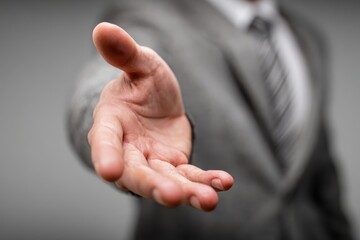 A businessman in a suit extends a hand. Use this for an offer or agreement concept.