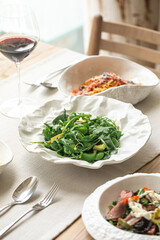 Healthy arugula salad with fresh avocado slices served on a designer plate, elegant table setting