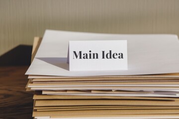 Struggle learning new skills concept. A stack of papers with a card labeled "Main Idea" on top, suggesting organization and focus.