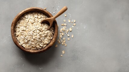 Elegant photo of rolled oats in a wooden bowl with a spoon on a gray concrete background.