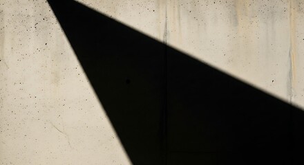 A stark shadow cast diagonally across a textured concrete wall creating a geometric contrast in light
