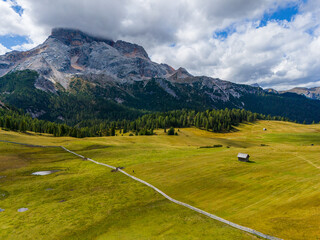 Beautiful landscape in Dolomites, Italy.  Malga Prato Piazza meadow and big mountain summit and ridge. South Tyrol region in Italy. Trekking and bike road in Italy Dolomites. Wooden cabin hut.