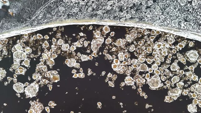 Top down abstract of snow or ice blocks swirling in fluid with organic motion pattern