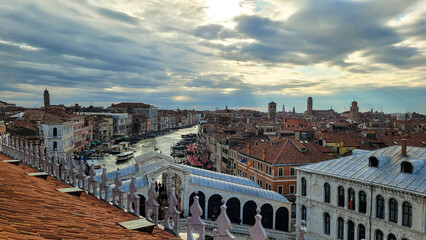 A stunning high-angle panoramic view of the Grand Canal and the iconic Rialto Bridge at sunset in Venice, Italy.