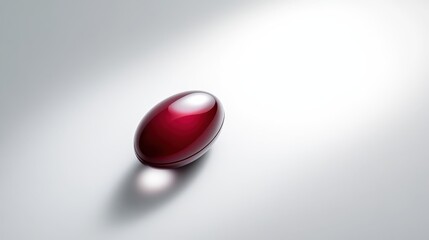 A glossy red capsule resting against a white backdrop