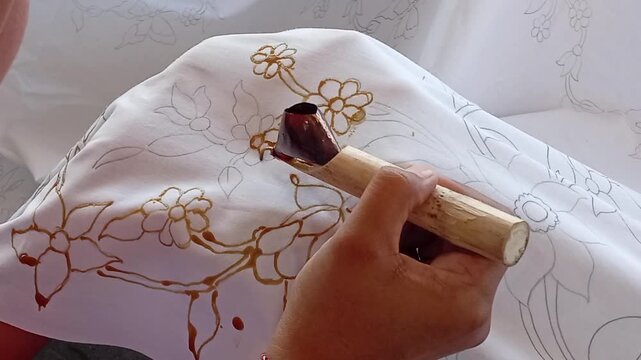 hand holding a canting to batik cloth