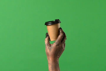 A creepy zombie hand holds a coffee cup