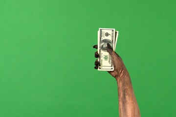 Creepy zombie hand hold a stack of cash