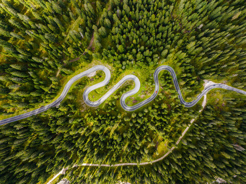 Beautiful mountain road in the forests of the Dolomites, Italy. Winding road in the Giau pass. Passo Giau serpentine. Famous road with many curves in the Dolomites mountains. Top view. Drone shot.